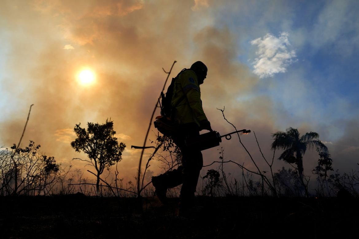 A firefighter sets the forest ablaze as part of a controlled plan to prevent wildfires in the Cerrado region, at a national park in Brasilia, Brazil