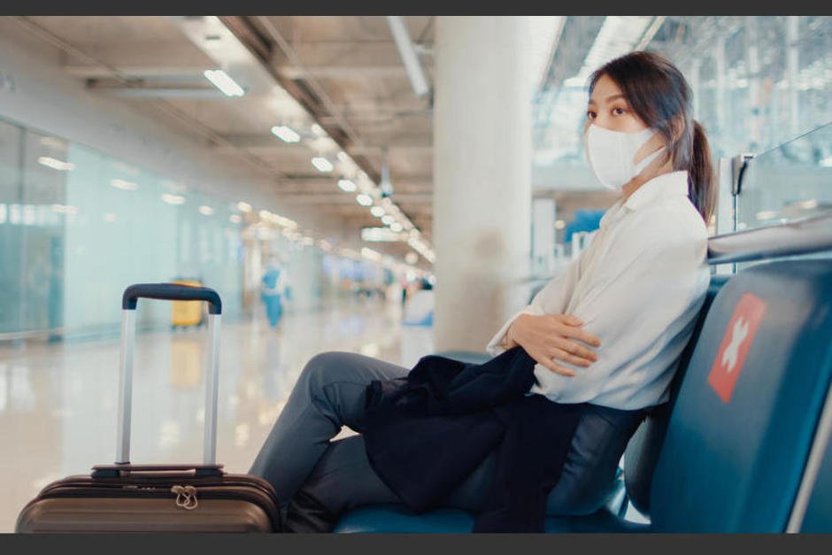 Asian business girl walk with luggage sitting in bench wait and look partner for flight at airport. Business travel commuter covid pandemic, Business travel social distancing, Business travel concept.