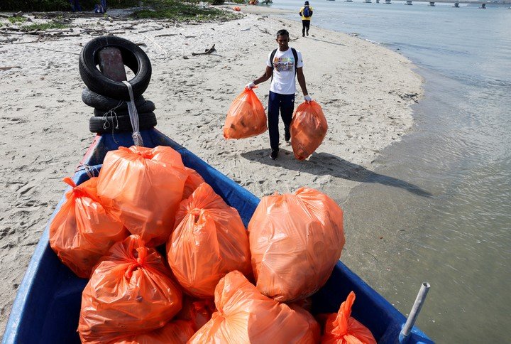 Un voluntario lleva botellas de plástico a un barco, recogidas durante una campaña de limpieza de playas organizada con motivo de la celebración del Día de la Tierra en George Town, Malasia, el 22 de abril de 2024. REUTERS/Hasnoor Hussain