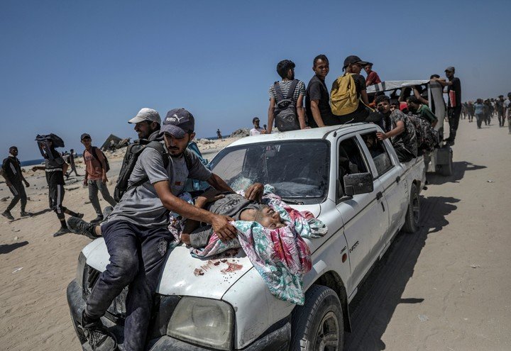 El cuerpo de un hombre es transportado sobre el capó de un coche tras ser abatido a tiros en un punto de distribución de alimentos cerca de Zikim, en el norte de la Franja de Gaza. Foto EFE