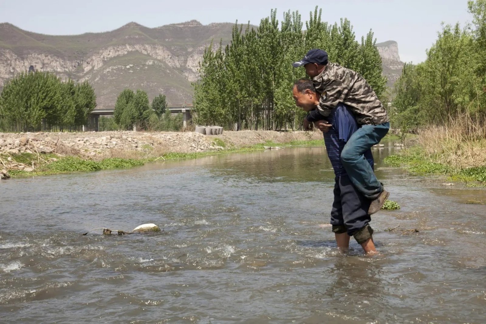 Al llegar al río, Haixia se apoya en la espalda de su amigo. Foto: AP